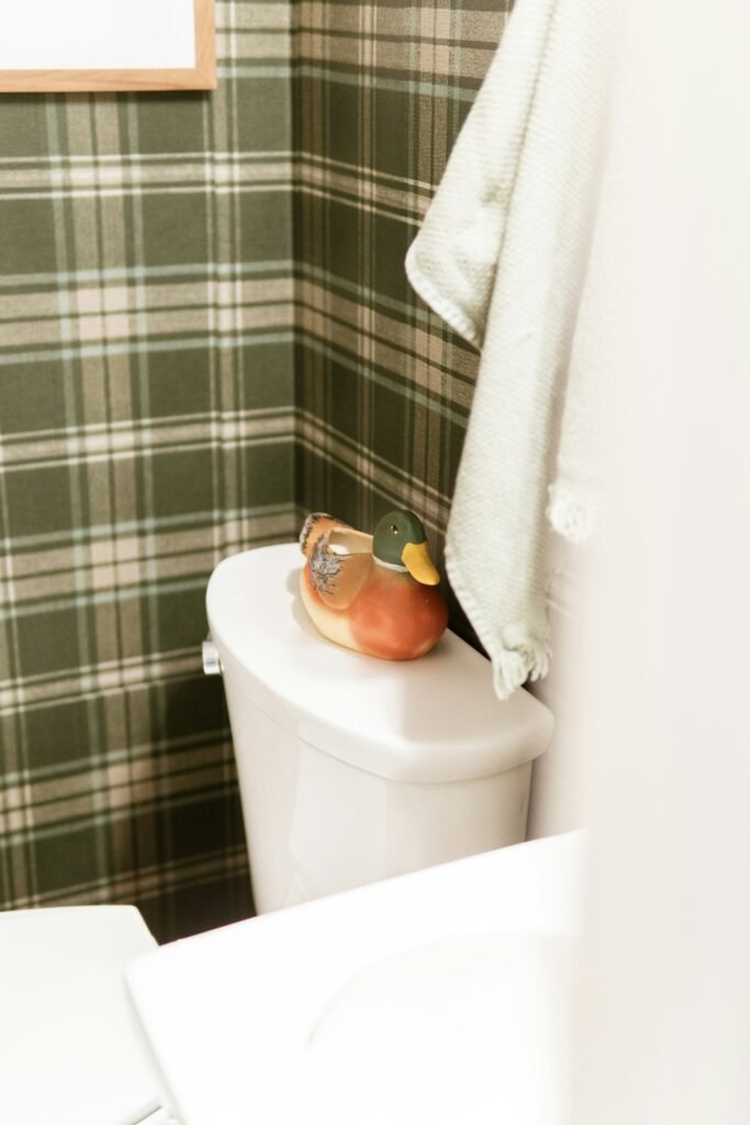 A red rubber plunger with a wooden handle beside a toilet